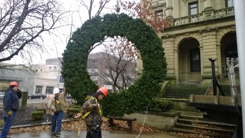 Hanging a large holiday wreath on a public building with a crane