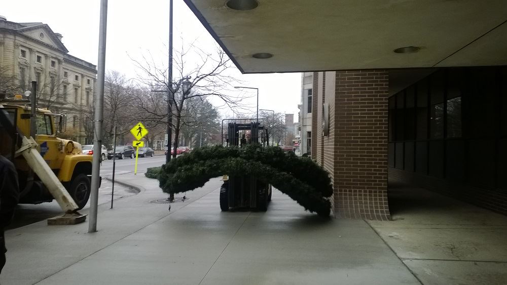 A large holiday wreath being carried by a small forklift 2